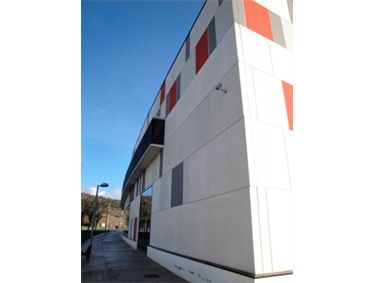 Un gran edificio blanco con rayas rojas y grises en los laterales.