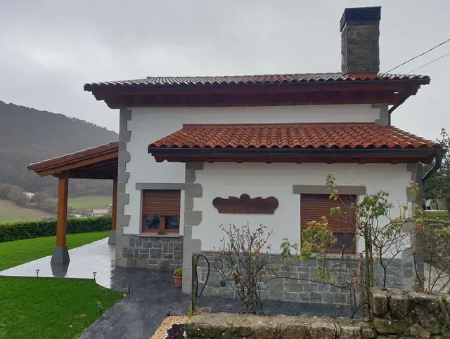 Una pequeña casa blanca con techo de tejas rojas