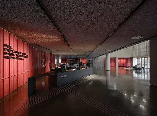 Un gran vestíbulo con una pared roja y un mostrador negro.