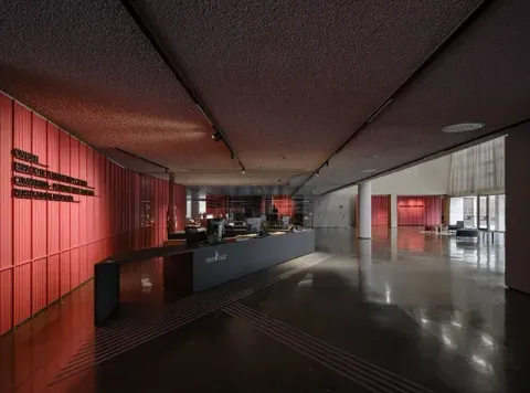Un gran vestíbulo con una pared roja y un mostrador negro.