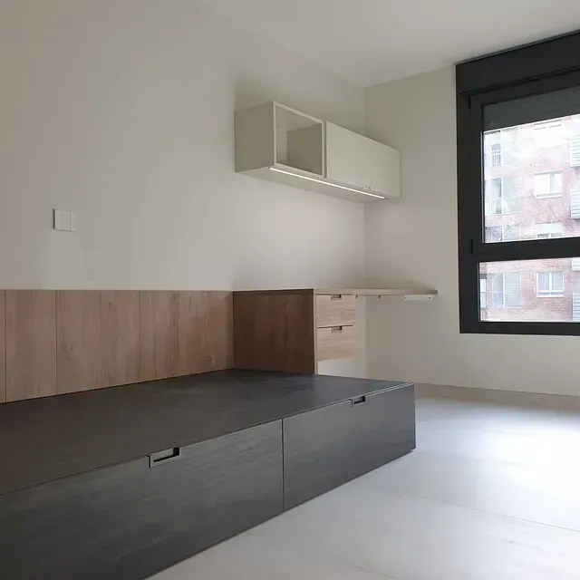 Hay una cama en el medio de la habitación con una ventana.