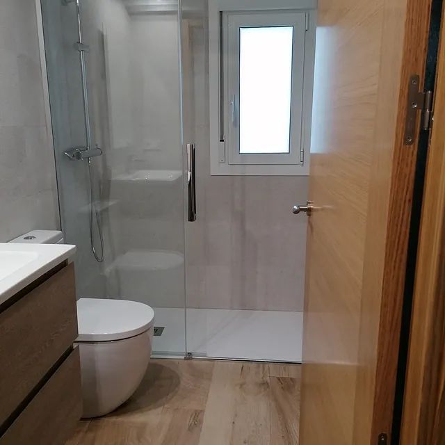 Un baño con inodoro, lavabo, ducha y ventana.