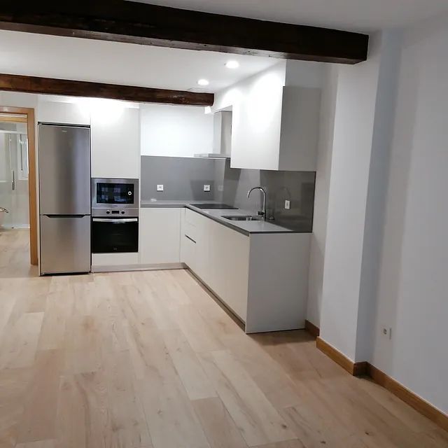Una cocina con gabinetes blancos y electrodomésticos de acero inoxidable.
