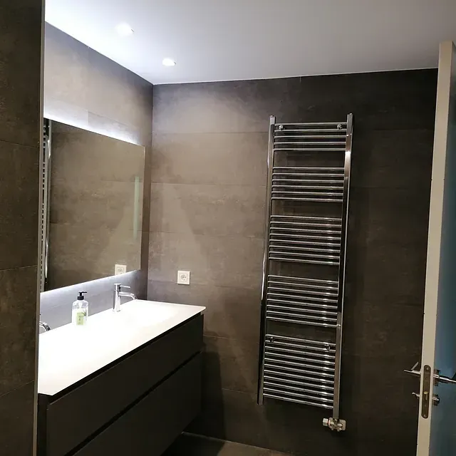 Un baño con lavabo, espejo y toallero.