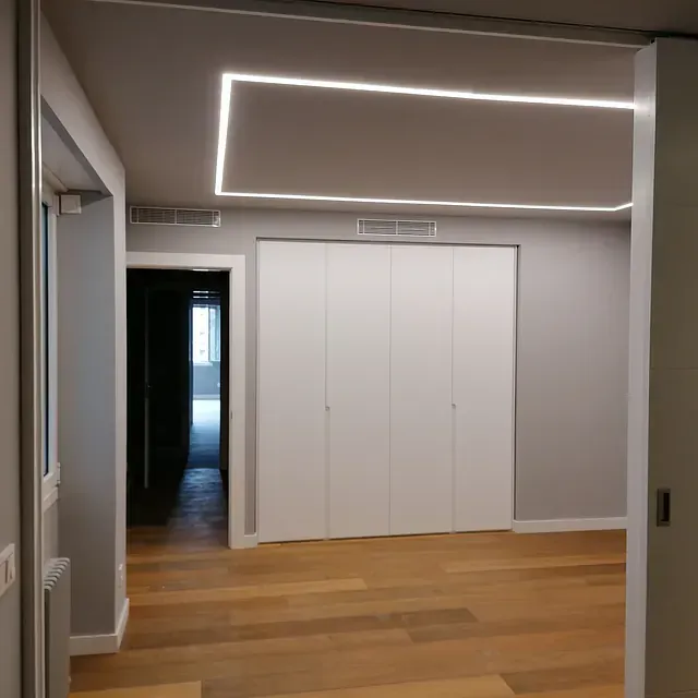 Una habitación vacía con armarios blancos y suelos de madera.