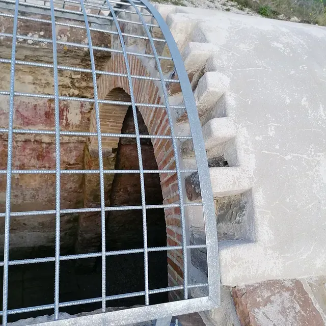 Un arco de ladrillo con una valla de metal alrededor.