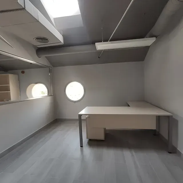 Una oficina vacía con un escritorio y una ventana.