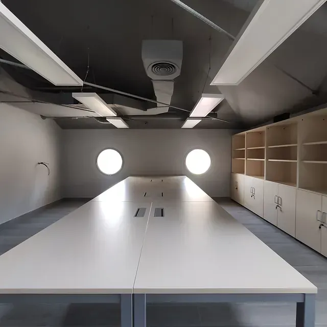 Una mesa blanca larga en una habitación con estantes.