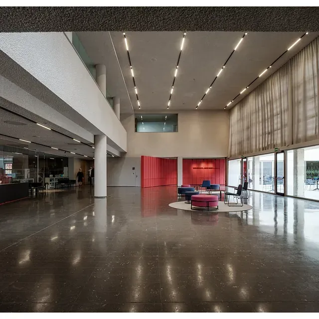 Una habitación grande con muchas ventanas y una pared roja.