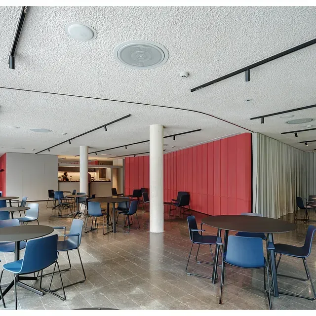 Una gran sala con mesas y sillas y una pared roja.