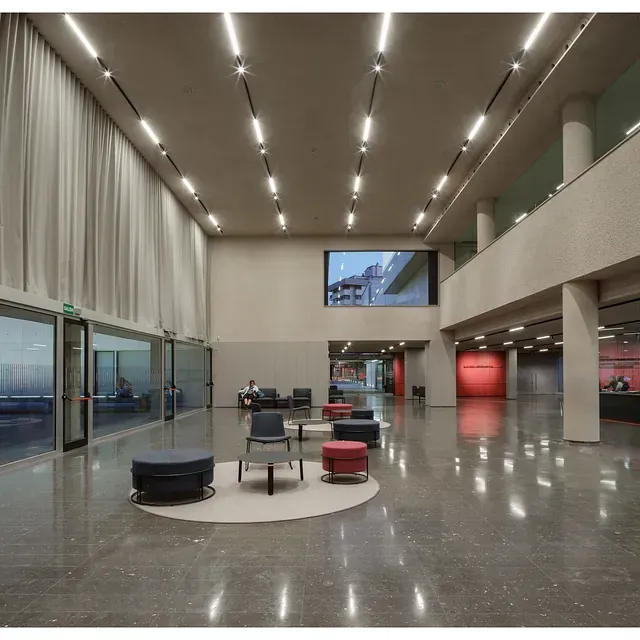 Una habitación grande con sillas y otomanas.