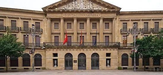 Un gran edificio con una bandera roja delante de él.
