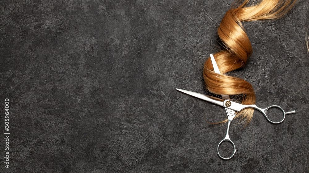 Eine Schere und ein Haarwirbel auf einer schwarzen Oberfläche