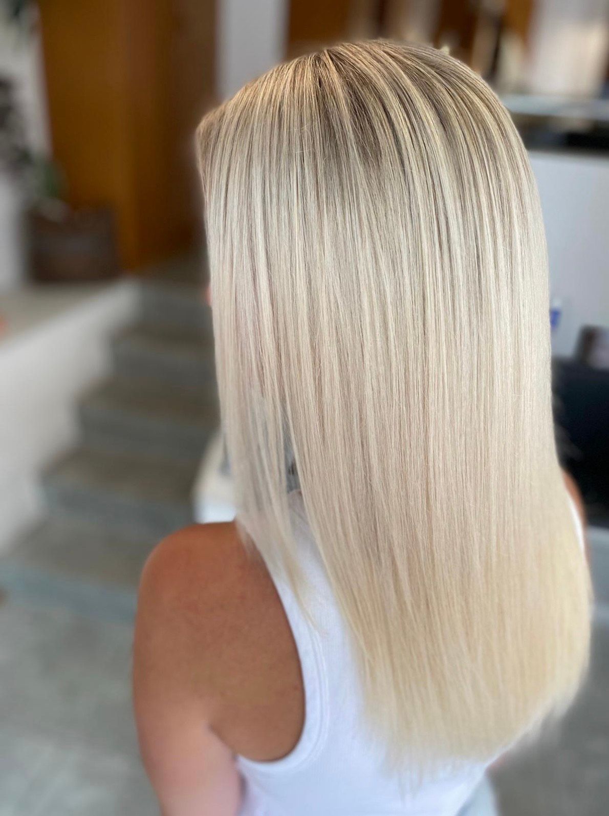 Frau mit langem, glattem, blondem Haar mit strukturierter, gekräuselter Optik an den Wurzeln.