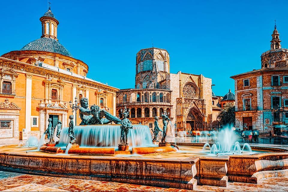 Er staat een fontein midden op een plein voor een gebouw.