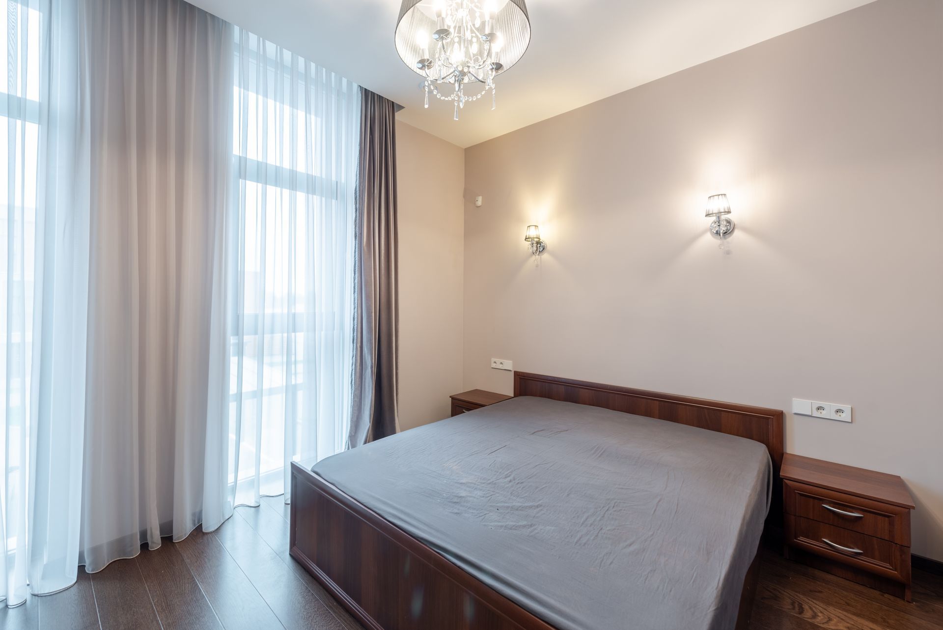 Ein Schlafzimmer mit einem grossen Bett, Nachttischen, Vorhängen und einem Kronleuchter