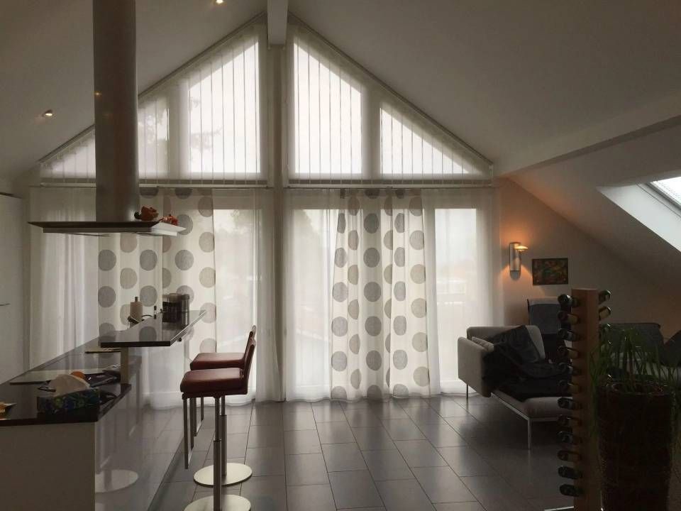 Ein Wohnzimmer mit vielen Fenstern und Vorhängen