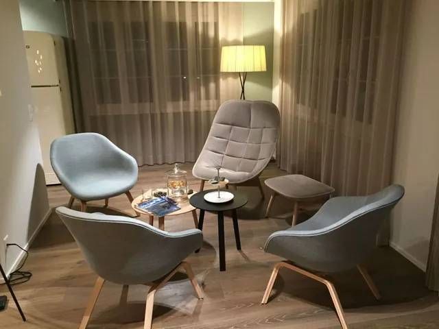 Ein Wohnzimmer mit Stühlen, einem Tisch, einer Lampe und Vorhängen. Foto von der rido GmbH