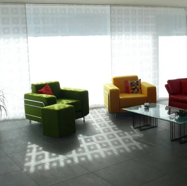 Ein Wohnzimmer mit Vorhängen, einem grünen Stuhl und einem gelben Stuhl