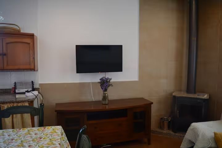 Sala de estar con TV montada, mueble de madera, chimenea y mesa de comedor.