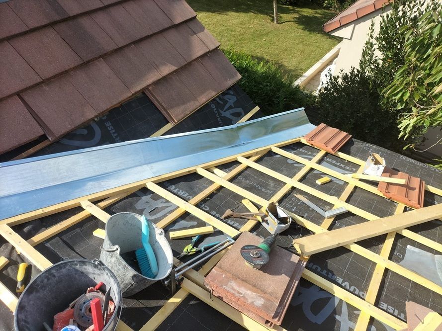 Réalisation de la couverture de l'extension avec pose de l'écran sous-toiture, des liteaux et des éléments de zinguerie avant la mise en place des tuiles.