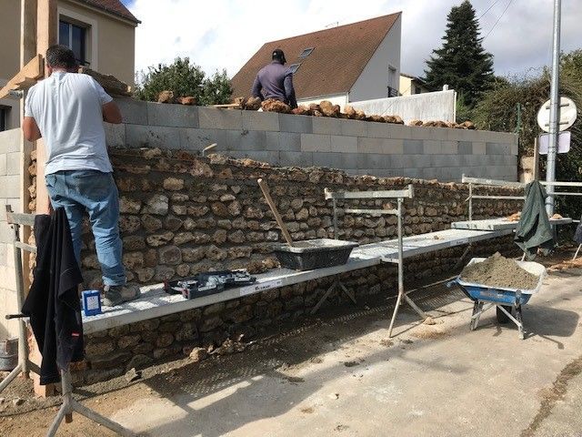 Habillage du mur en parpaing avec de la pierre meulière récupérées.