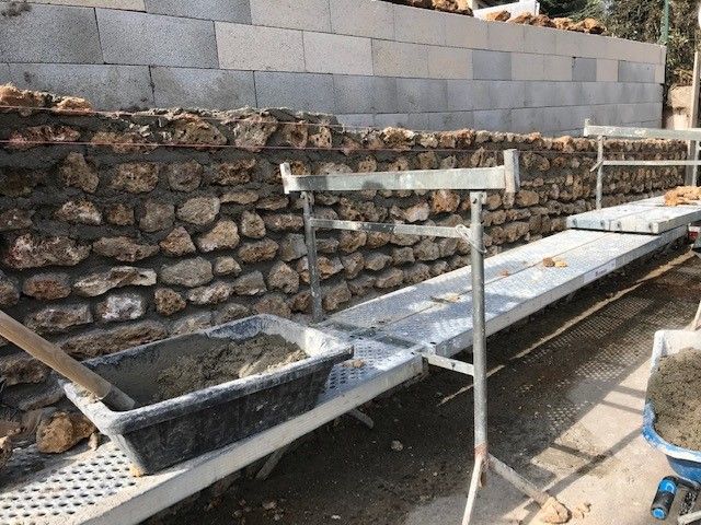 Habillage du mur en parpaing avec de la pierre meulière récupérées.