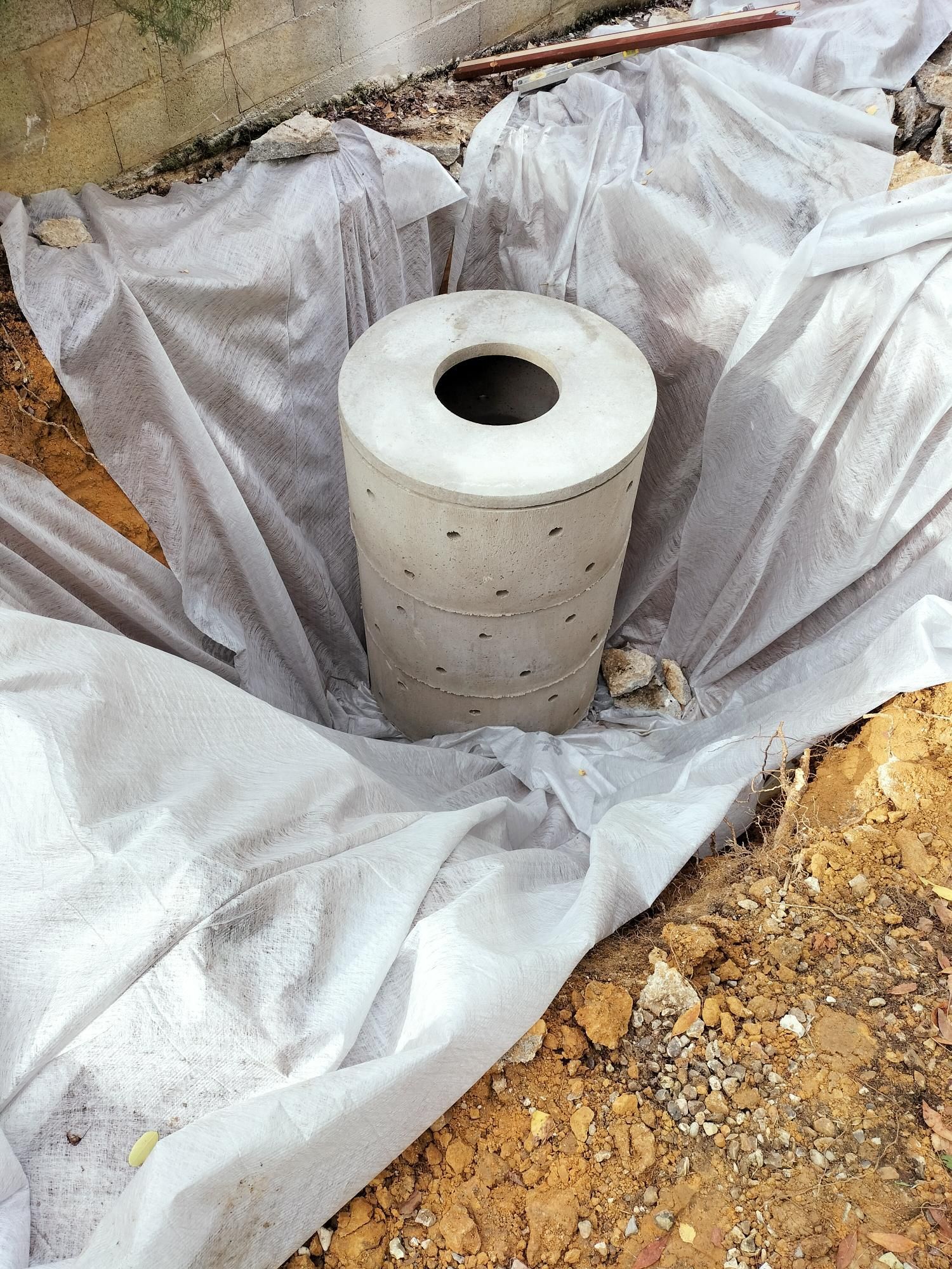 Tuyau ou conduit d’aération cylindrique blanc, dressé dans une fosse d’excavation tapissée de plastique et entourée de terre
