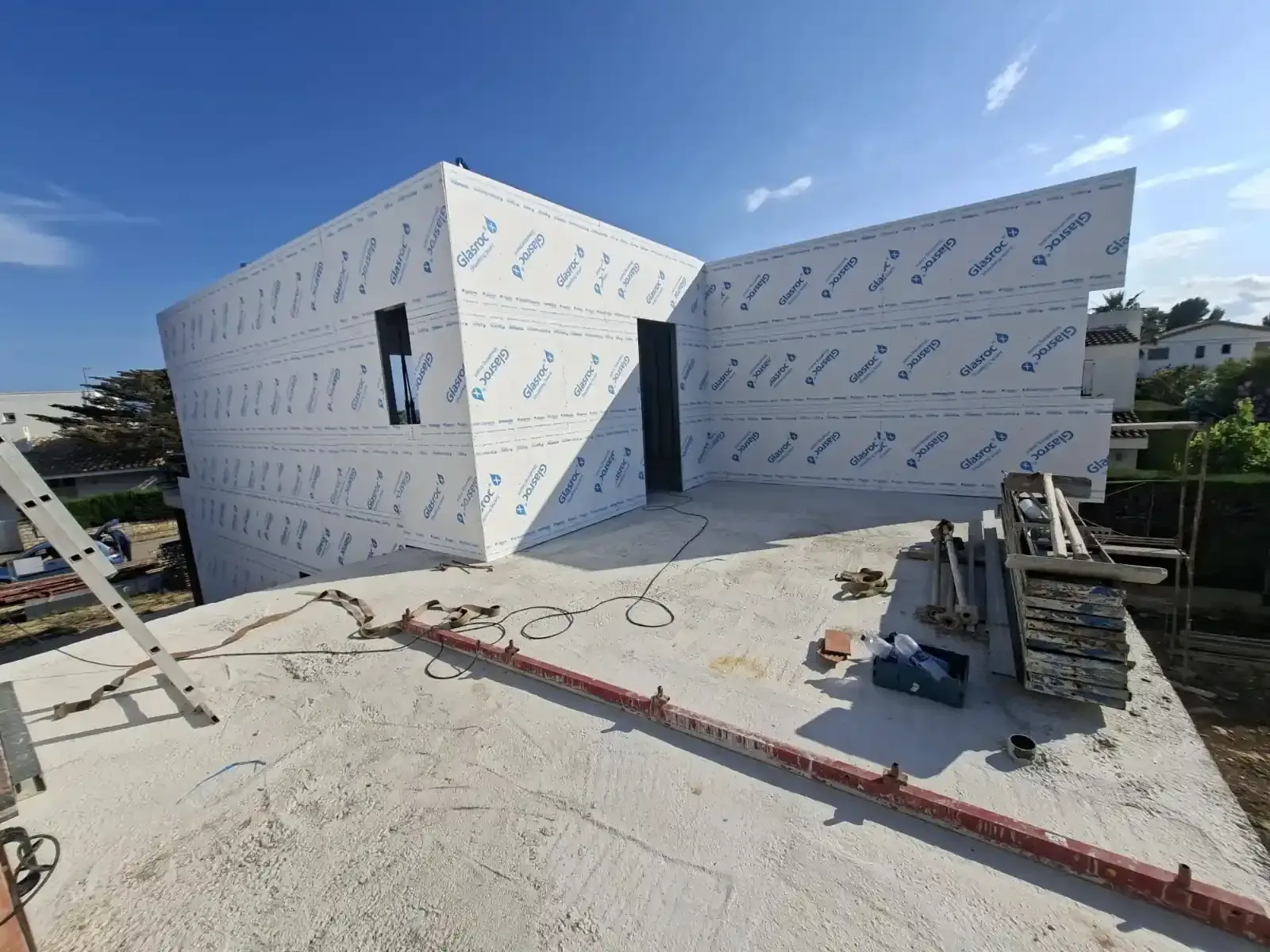Techo en construcción con paneles de revestimiento blancos y una escalera en un día soleado.