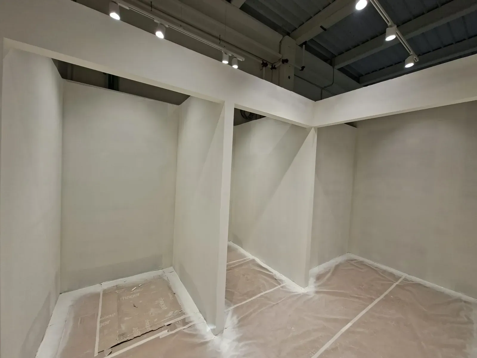 Cubículos de exposición blancos y vacíos en un espacio de galería en construcción.
