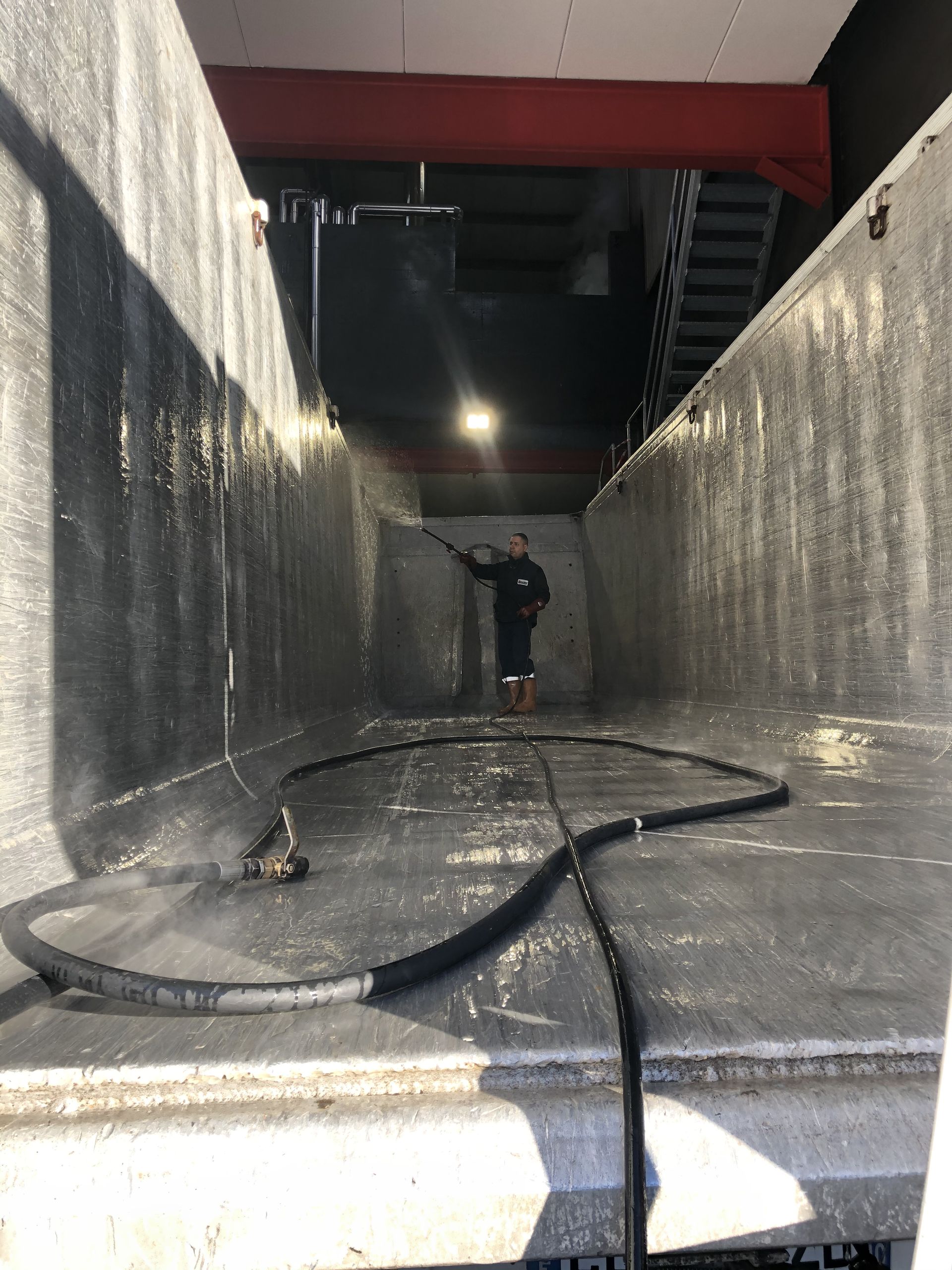 Un hombre está limpiando un tanque grande con una manguera.