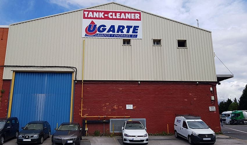 Una fila de autos están estacionados frente a un edificio de limpieza de tanques.