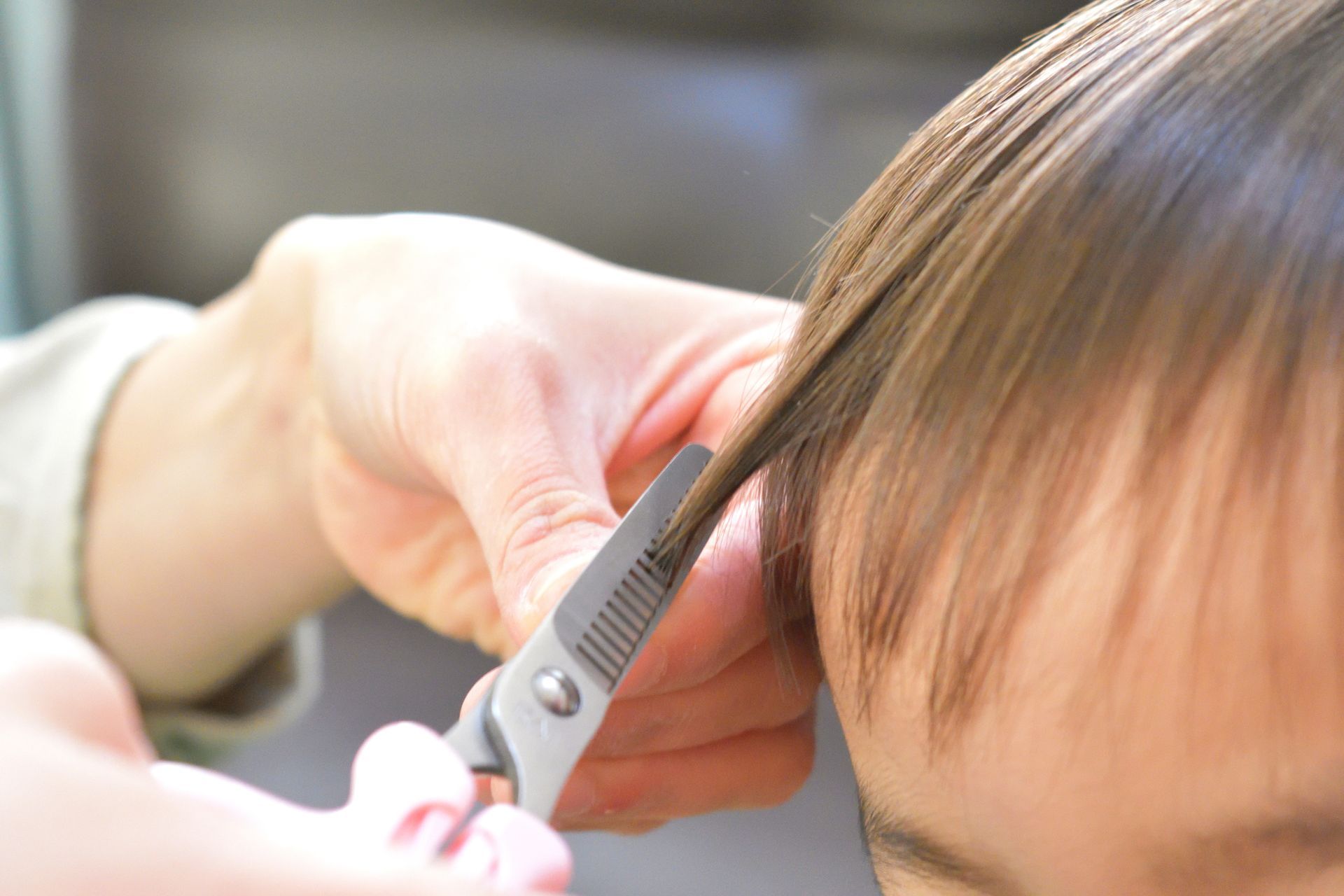 Une coiffeuse coupe les cheveux d'un enfant