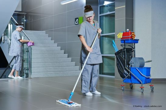 Zwei Reinigungskräfte putzen in einem Flur