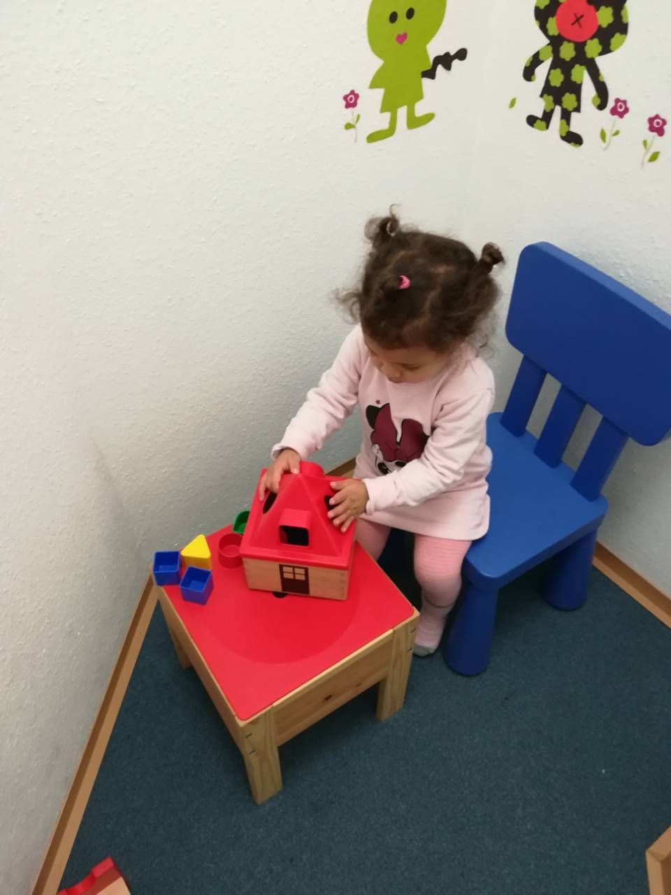 Junges Mädchen sitzt am Tisch und spielt mit Blöcken bei der Ergotherapie