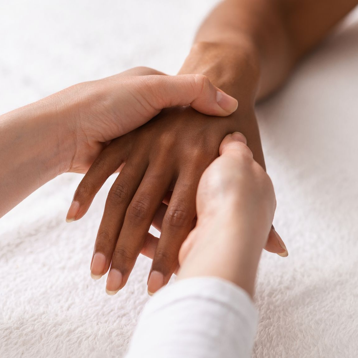 Des mains de différentes teintes de peau recevant un massage des mains.