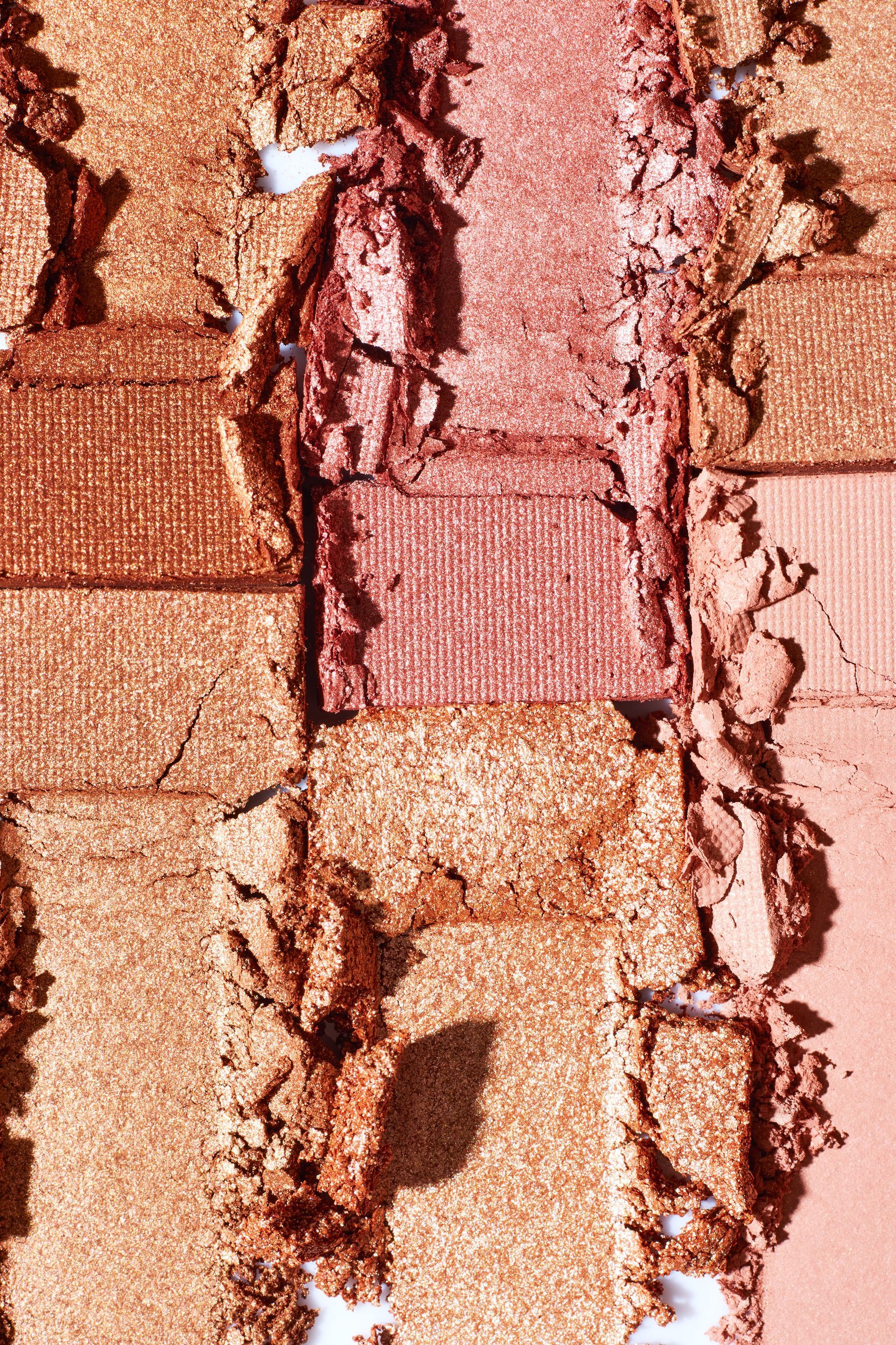 Palette de fards à paupières écrasés dans des tons d'or, de bronze et de rose, disposés verticalement.