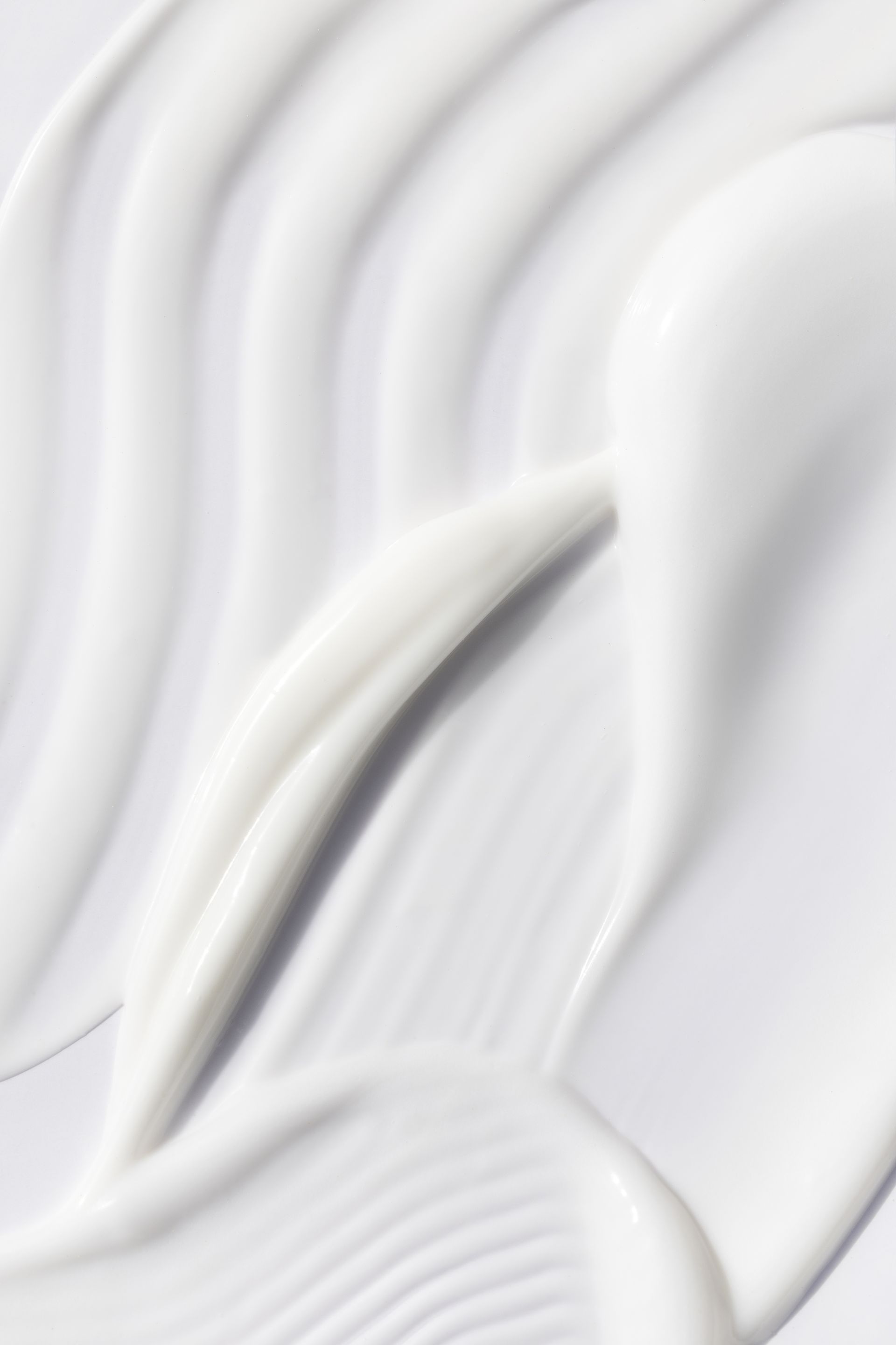 Crème blanche tourbillonnante, texture lisse, avec des ombres et des reflets doux.