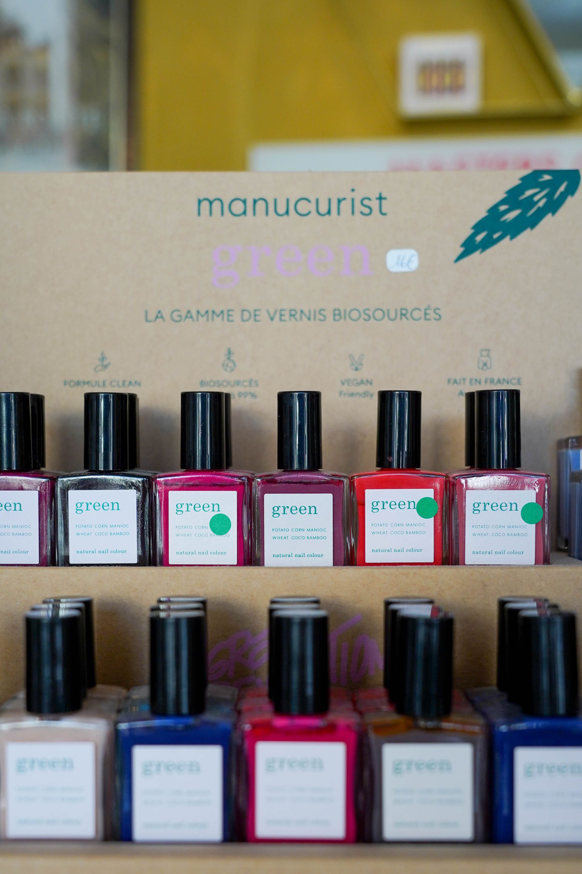 Affichage de flacons de vernis à ongles verts Manucurist de différentes couleurs sur une étagère.