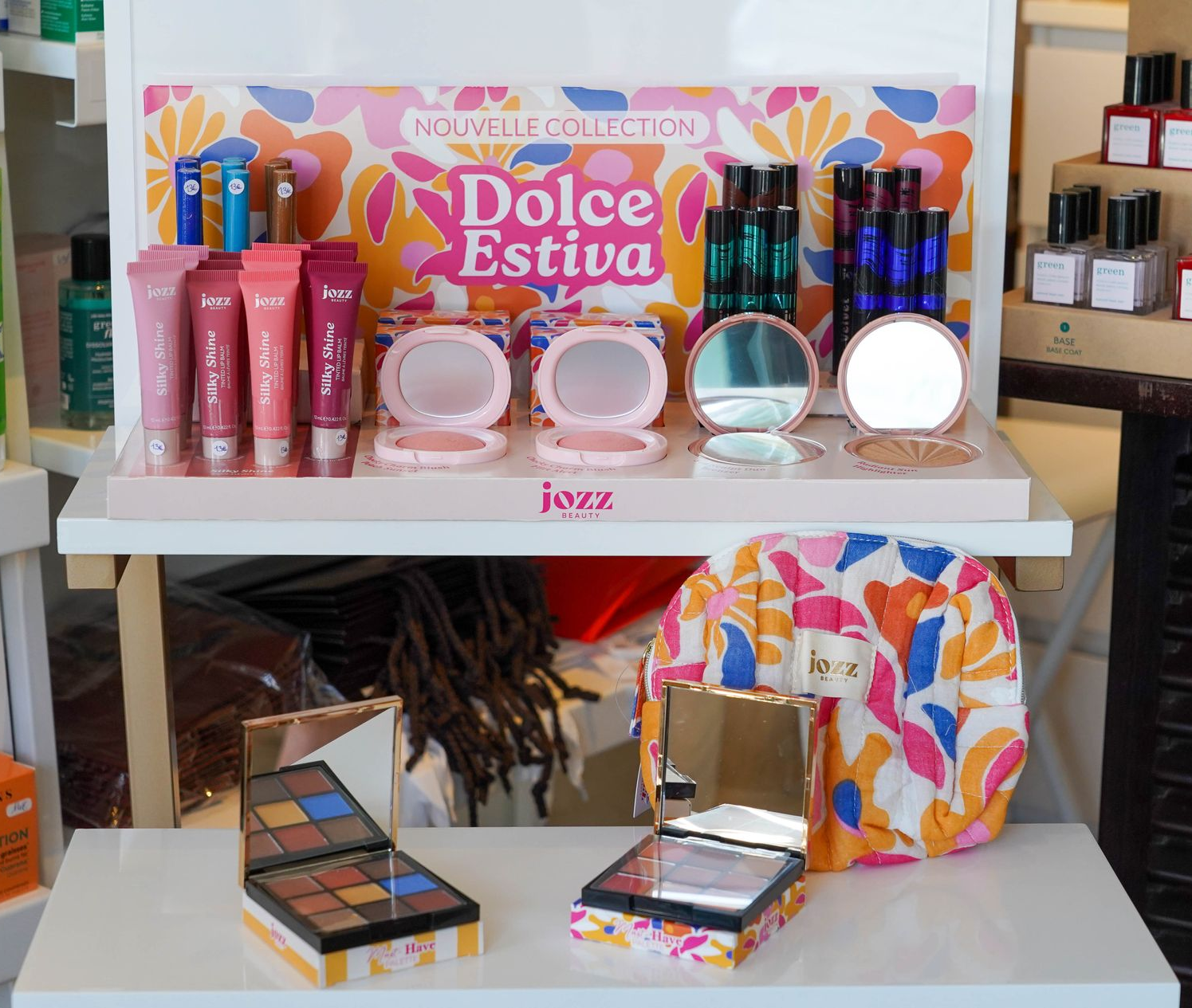 Femme souriante, se faisant retoucher la joue avec un pinceau de maquillage ; décor de studio.