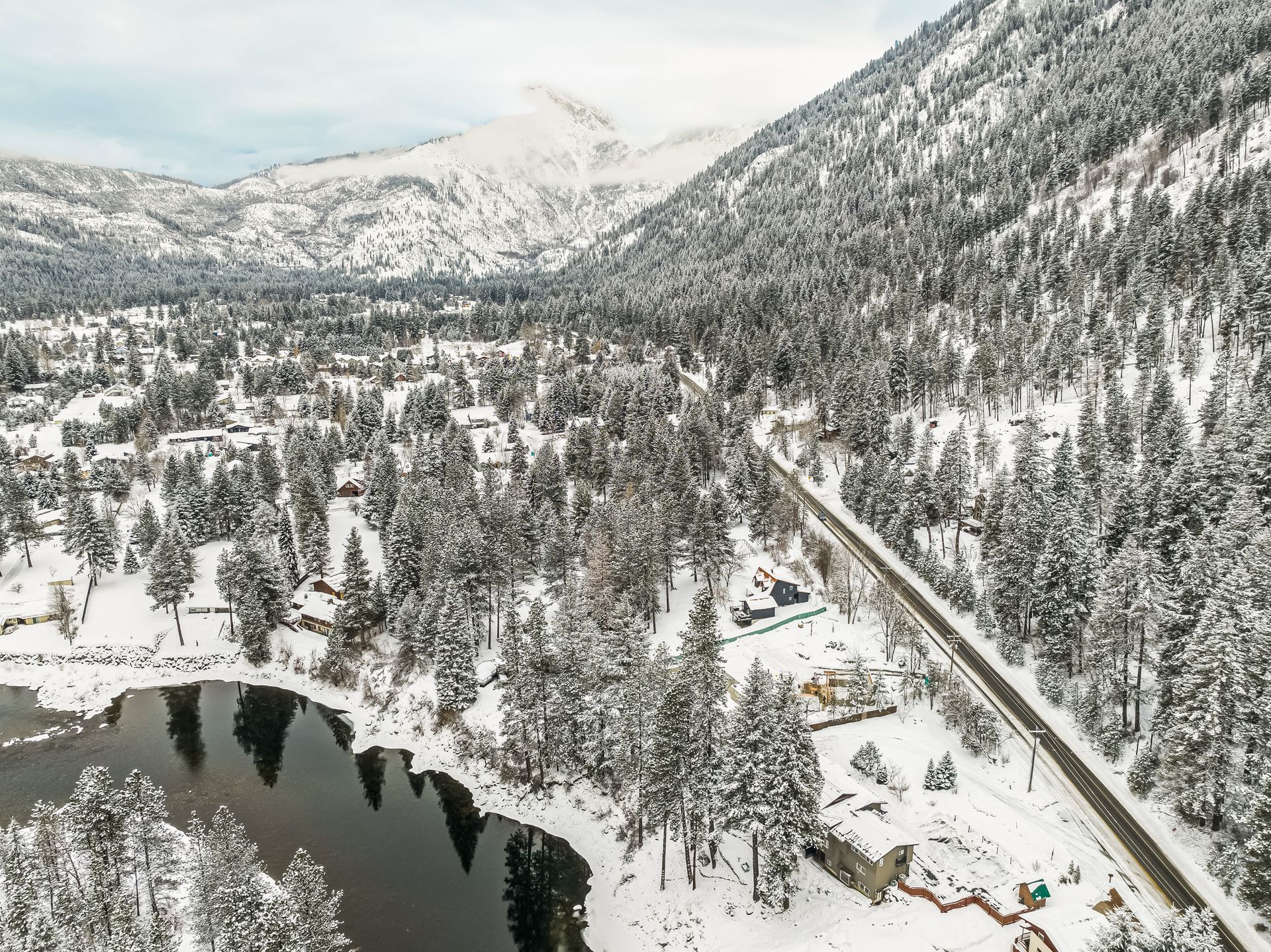 An aerial view of a snowy landscape with a lake and mountains in the background.