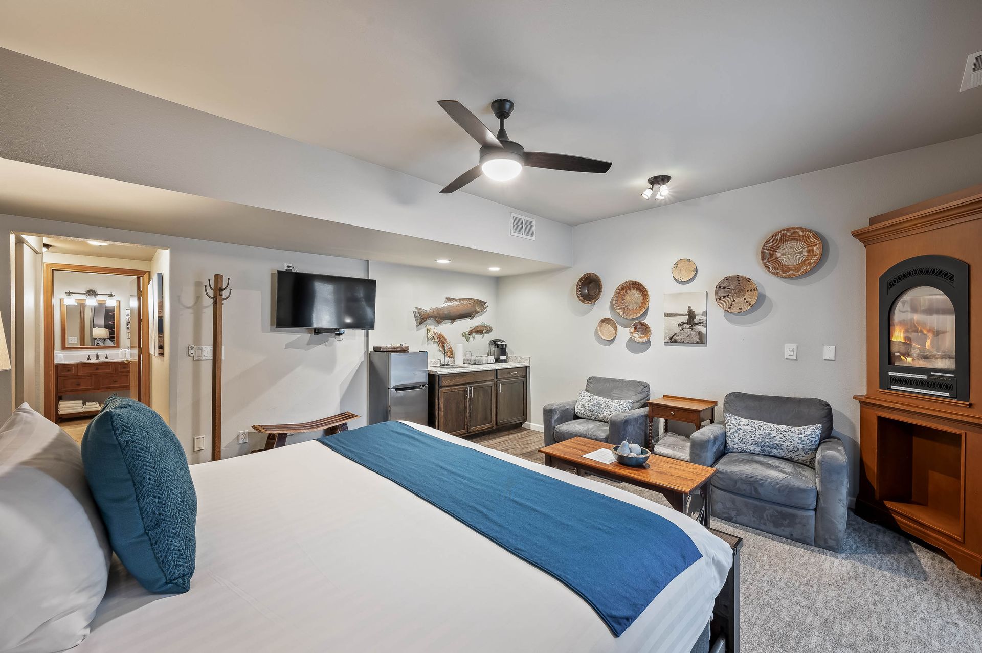 A hotel room with a king size bed and a ceiling fan.