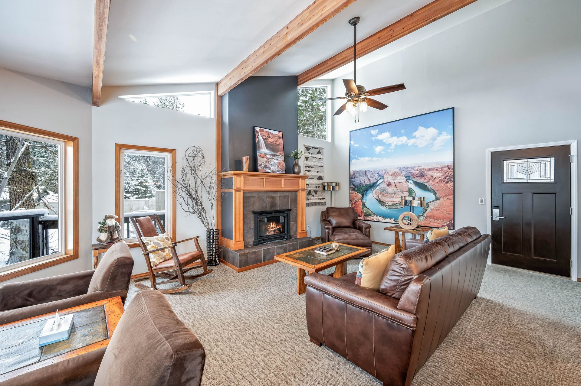 A living room with a couch , chairs , a fireplace and a ceiling fan.