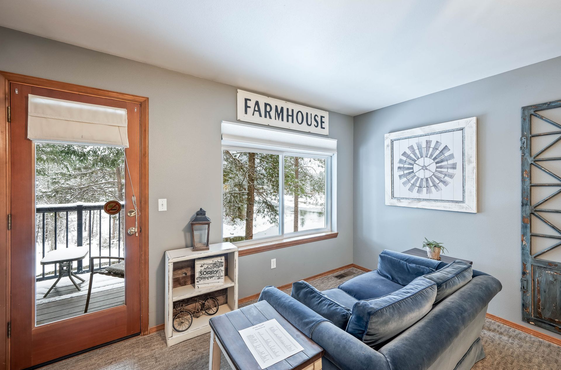 A living room with a couch and a sign that says farmhouse on the wall.