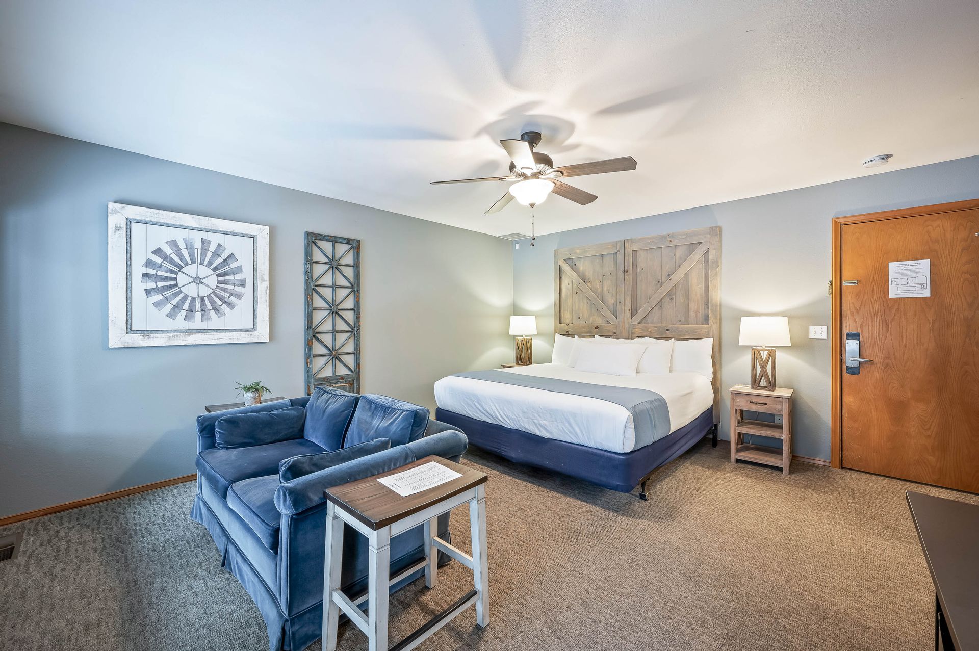 A hotel room with a king size bed , a couch , and a ceiling fan.