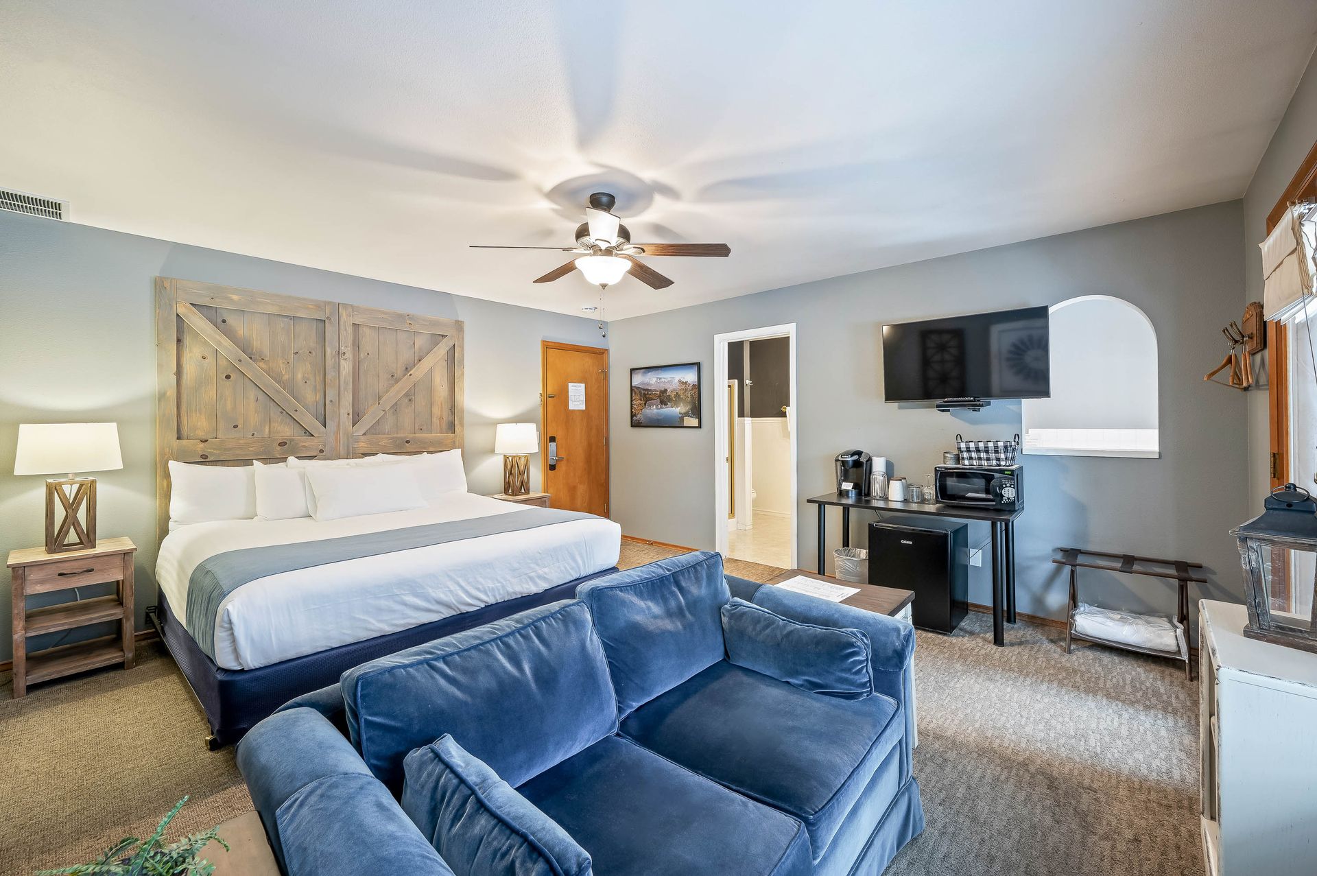 A hotel room with a king size bed and a blue couch.