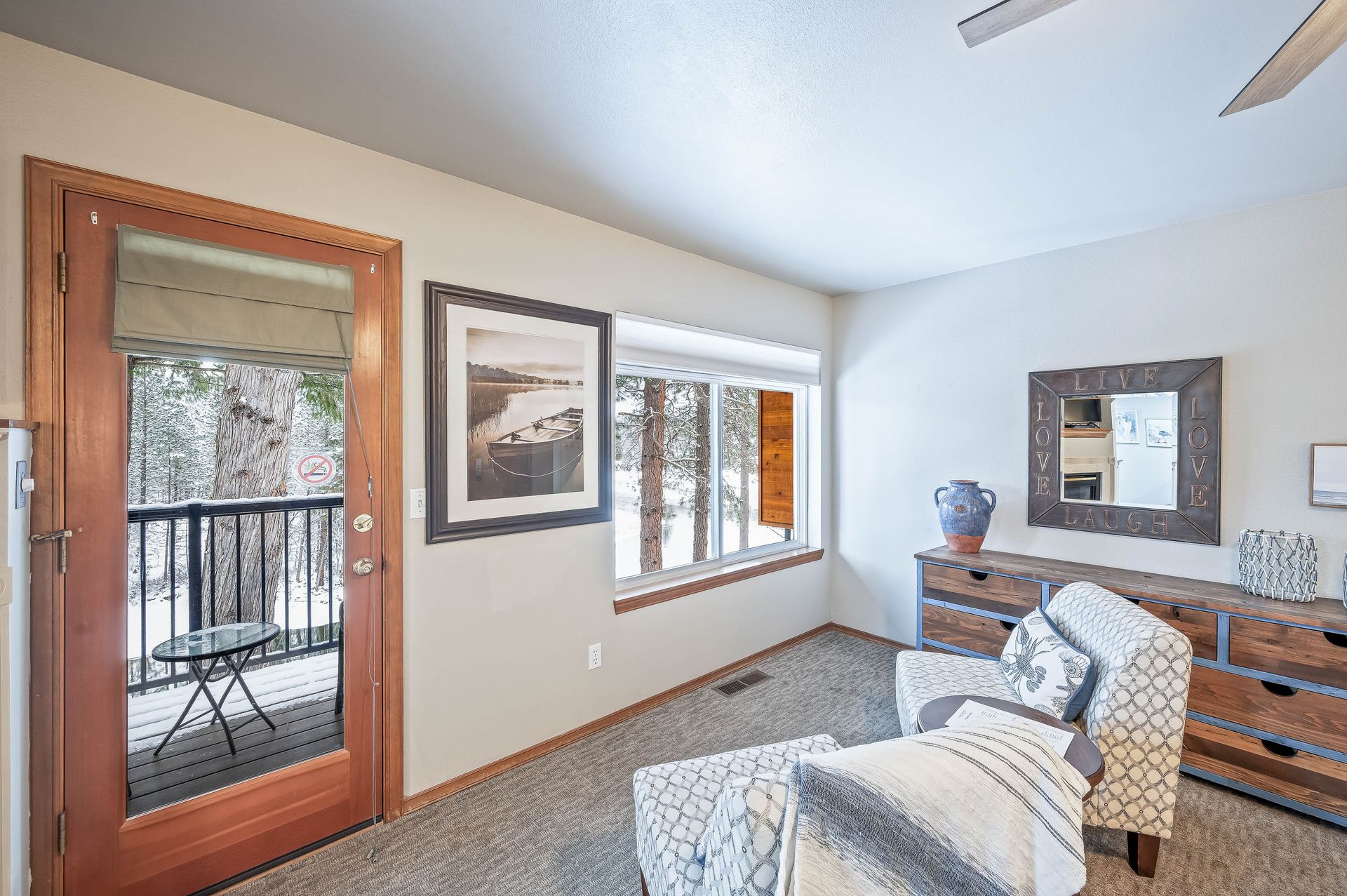 A living room with a couch , chair , dresser , mirror and sliding glass door leading to a balcony.