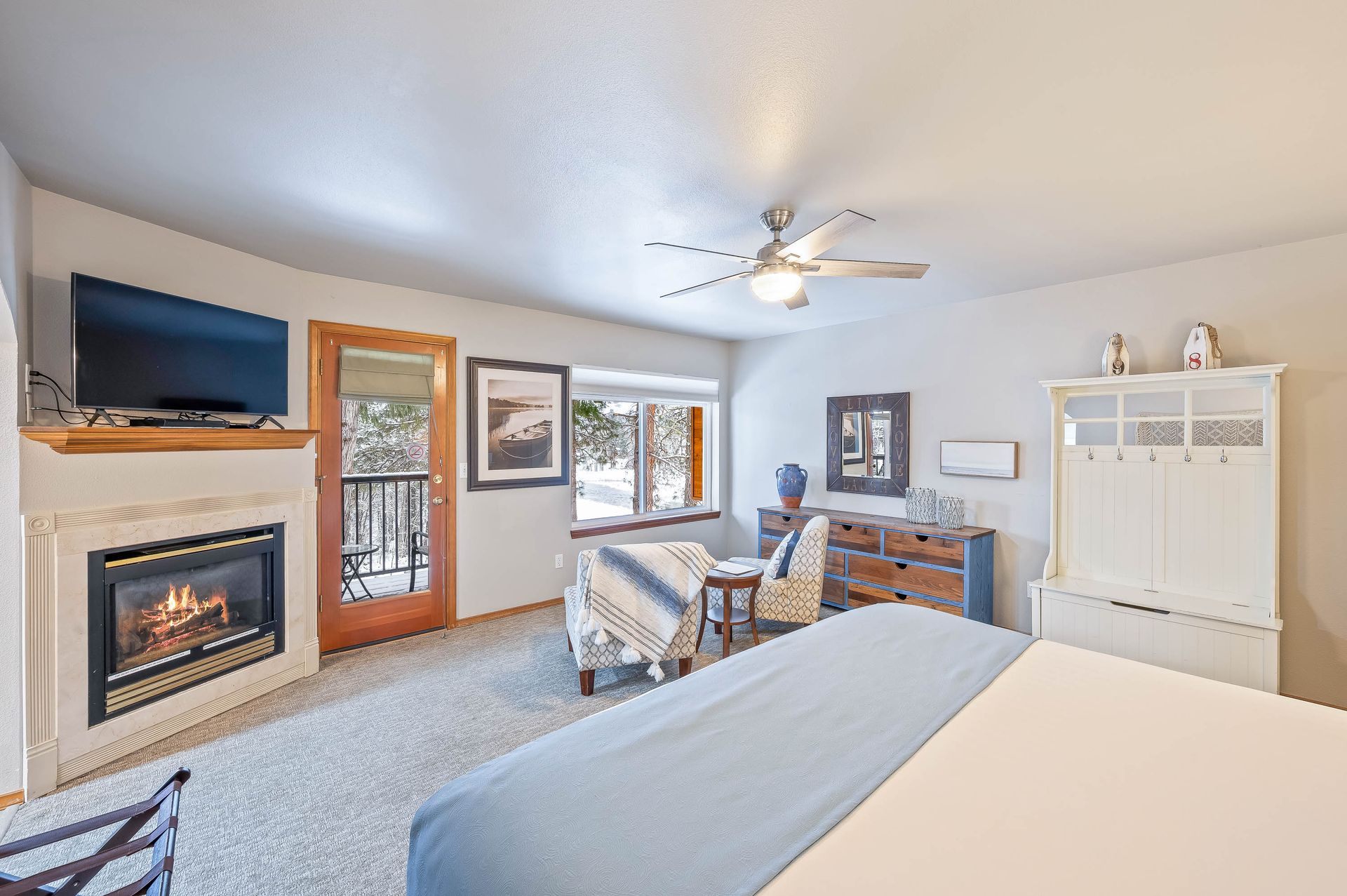 A bedroom with a king size bed , fireplace , television and ceiling fan.