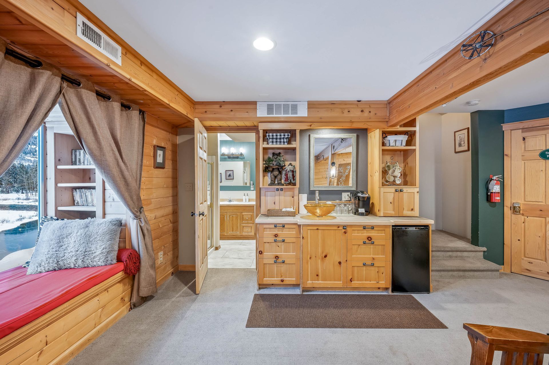 A living room in a log cabin with wooden cabinets and a large window.