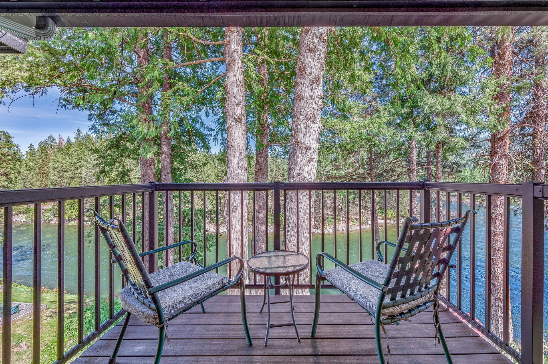A balcony with two chairs and a table overlooking a lake.